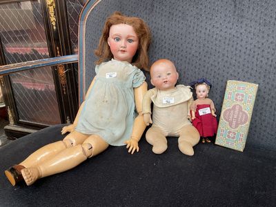 two dolls sitting next to each other on a chair