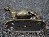 a bronze statue of a dog laying down on the ground