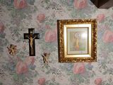 un tableau accroché au mur, au-dessus d'un crucifix et d'une croix