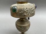 a silver vase with a blue and green decoration on it