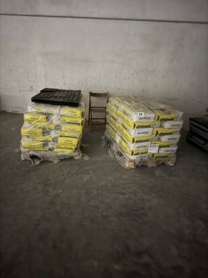 deux piles de palettes contenant un matériau jaune dans un entrepôt