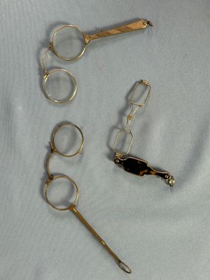 plusieurs paires de ciseaux et une paire de lunettes posées sur un tissu blanc