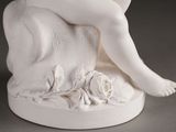 a white statue of a woman sitting on a rock