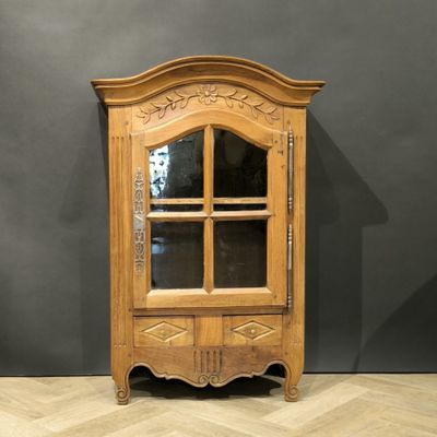 une vieille armoire en bois avec une porte vitrée, posée sur un parquet