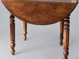 an oval table with turned legs and a wooden top