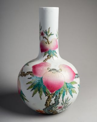 un vase blanc orné de fleurs roses, posé sur une surface grise