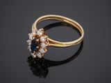 a close up of a gold ring with a sapphire and diamonds
