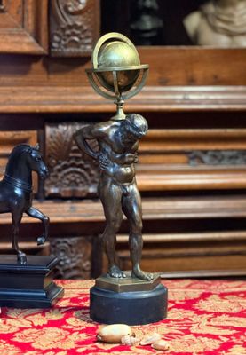 une statue représentant un homme tenant un globe terrestre, à côté d'une statue représentant un cheval