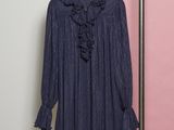 the shirt is hanging on a hanger in front of a pink wall