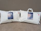 two white pillows sitting on top of a bed next to each other