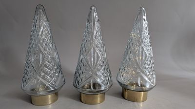 three clear glass christmas trees with gold bases on a white background