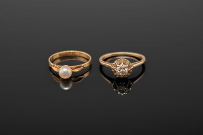 deux bagues en or ornées de perles et de diamants sur un fond noir