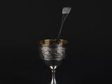 a silver cup with a spoon sticking out of it on a black background