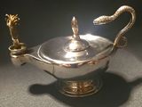 an antique silver plated teapot with a snake handle on a black surface