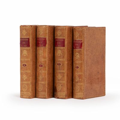 trois vieux livres posés l'un sur l'autre sur une surface blanche