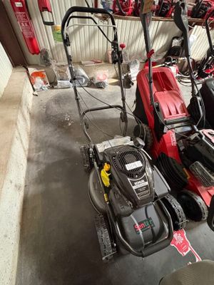 Plusieurs tondeuses à gazon sont alignées en rang dans un garage