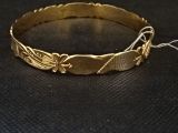 gros plan d'un bracelet en or sur une surface noire