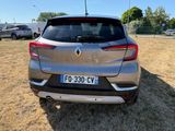 the rear end of a silver car parked in a field