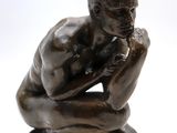 statue of a man sitting on his knees with his hand on his chin