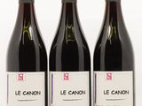 trois bouteilles de vin sont alignées sur une surface blanche