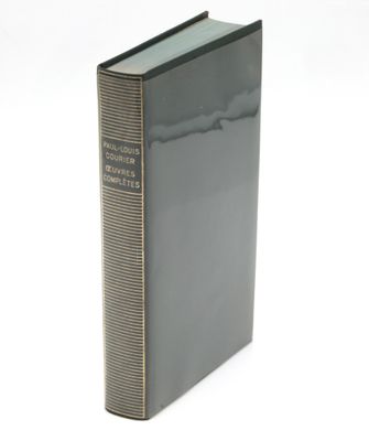 an old book sitting on top of a white table next to a white wall