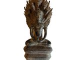 statue of a person sitting on a rock with a bird on his head