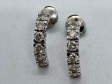 une paire de boucles d'oreilles créoles en diamant posées sur une surface blanche