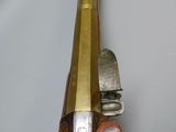 a wooden gun with a brass handle on a white wall