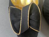 a pair of black shoes with a gold bow on them