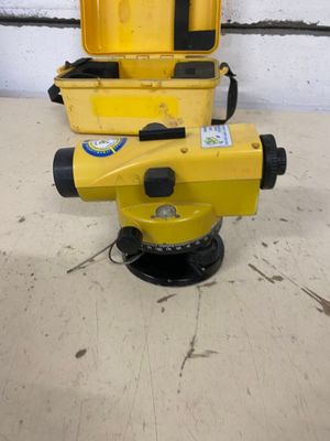 a close up of a yellow surveying device sitting on top of a cement floor