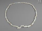 un gros plan d'un collier composé de perles blanches sur un fond gris