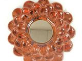 an orange flower shaped mirror hanging on a white wall