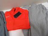 a red jacket and grey pants sitting on a shelf