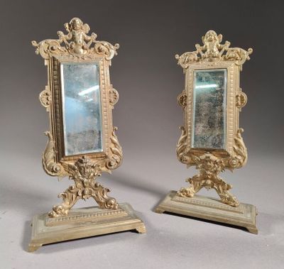 pair of antique mirrors on stands on a grey background