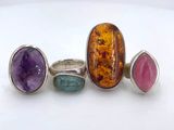 three rings with different colored stones on a white surface