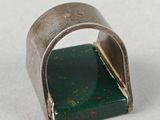 a close up of a metal ring with a green stone in it