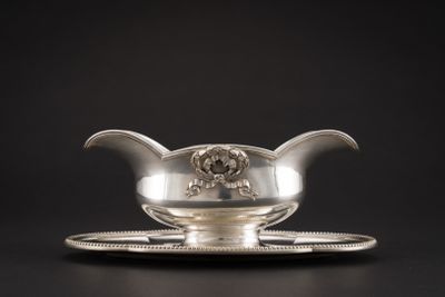 une saucière ancienne en argent posée sur un plateau, sur fond noir