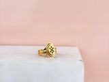 une bague en or posée sur un bloc de marbre, sur fond rose