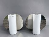 une paire de miroirs ronds avec des socles blancs posés sur un support gris