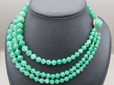 a green beaded necklace on a black mannequin