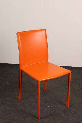 an orange chair sitting in a room with a white wall