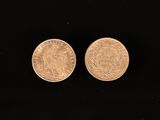 two gold coins are shown on a black surface
