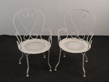 pair of white wrought garden chairs on black carpeted floor