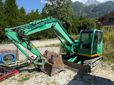 a green excavator that is sitting in the dirt