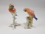 two figurines of parrots sitting on a branch