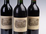 three bottles of wine are lined up on a white surface