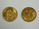 two gold coins sitting on top of a white surface next to each other