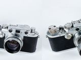 two old cameras sitting next to each other on a white surface