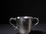 a silver cup on a black surface with a black background