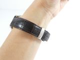 someone is holding a wrist with a black leather strap on it